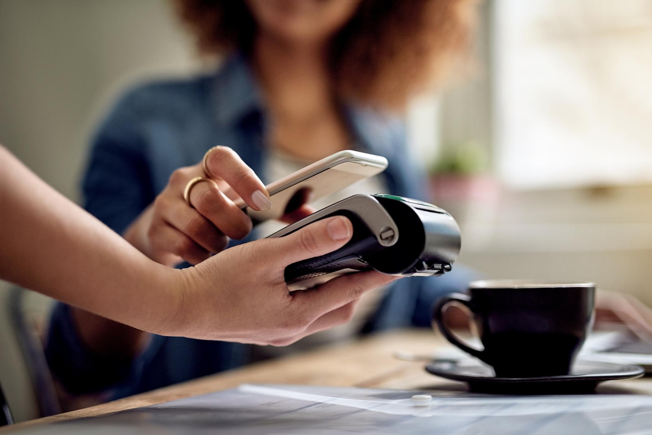A woman holds her phone to a scanner to make a payment