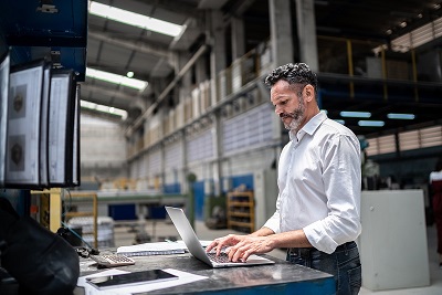A man works on his laptop inside of a large industrial warehouse