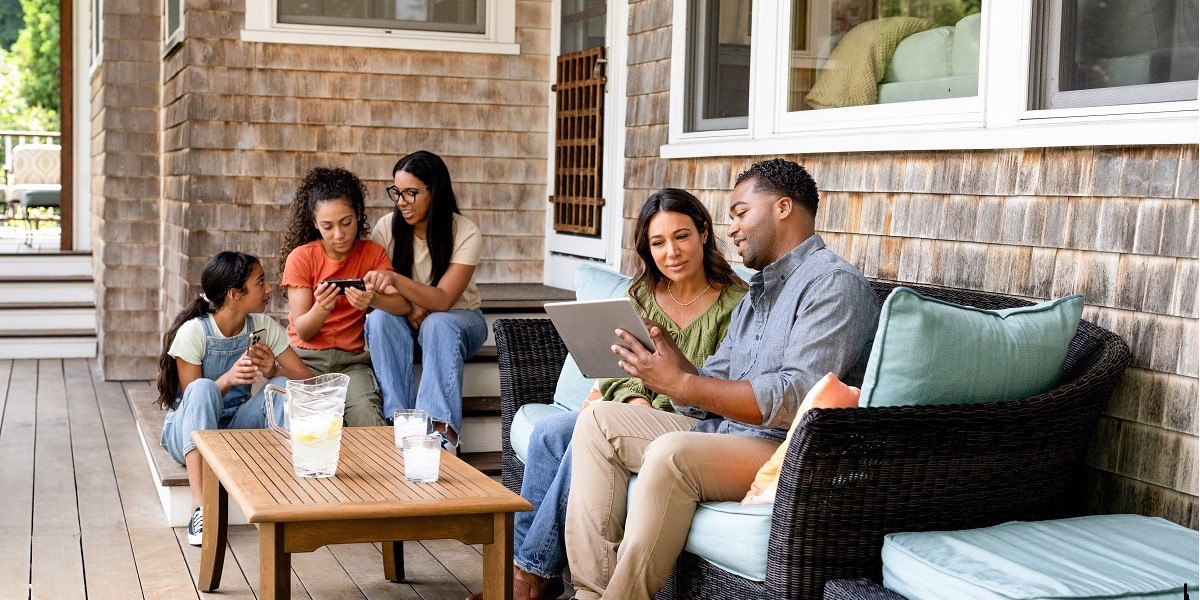 A family sits outside of their newly renovated home enjoying time together in their new space