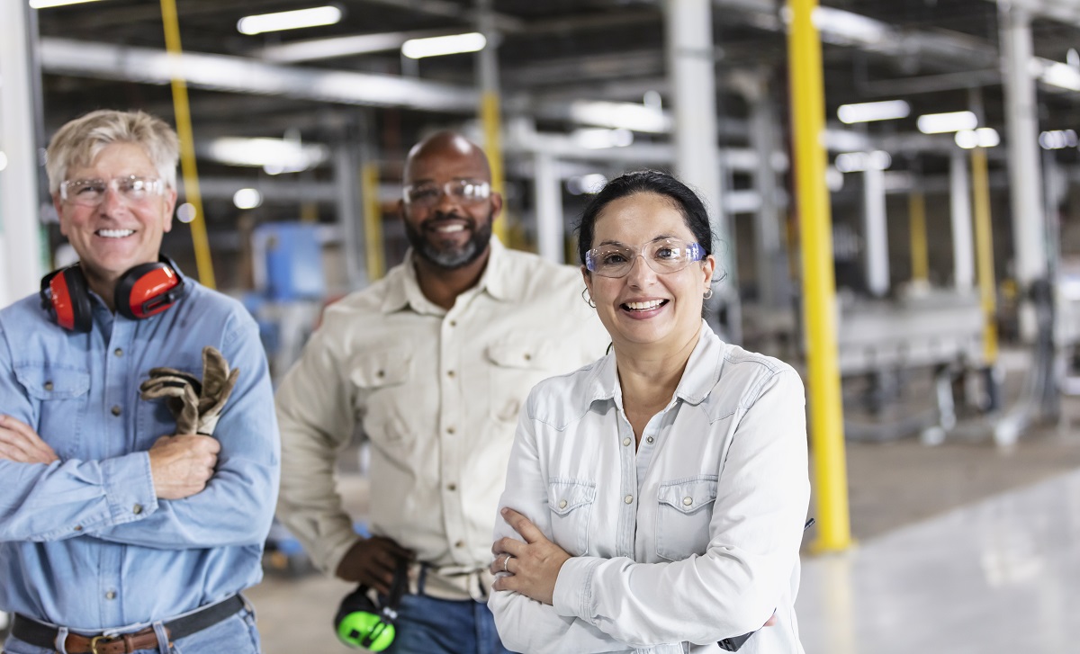 Colleagues stand together in a commercial facility and smile at the camera