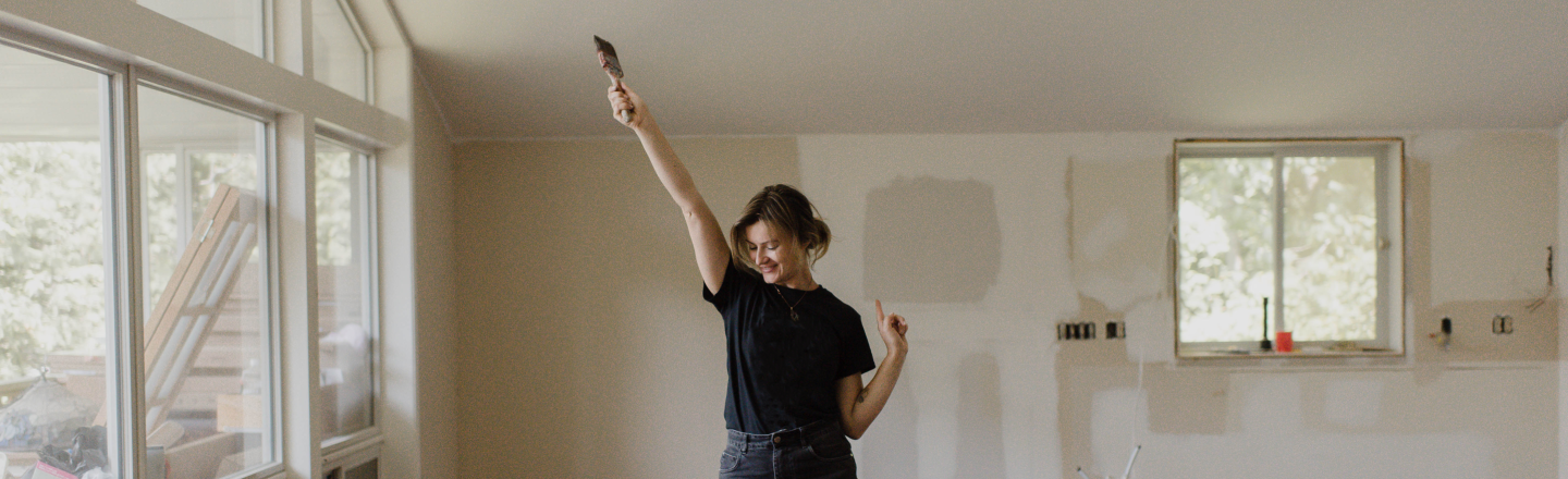 A woman stands in her newly renovated room excited to paint the walls