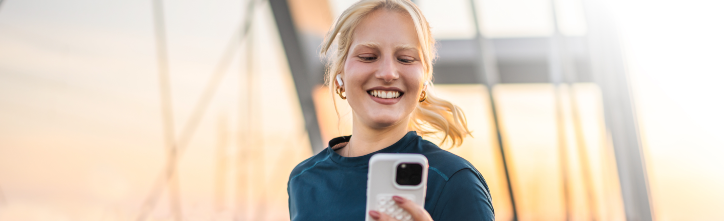 A woman checks her banking app on her phone while out for a run in Boston