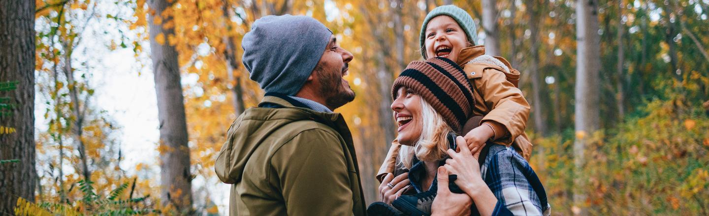 A family walks through the woods on an autumn day with their toddler