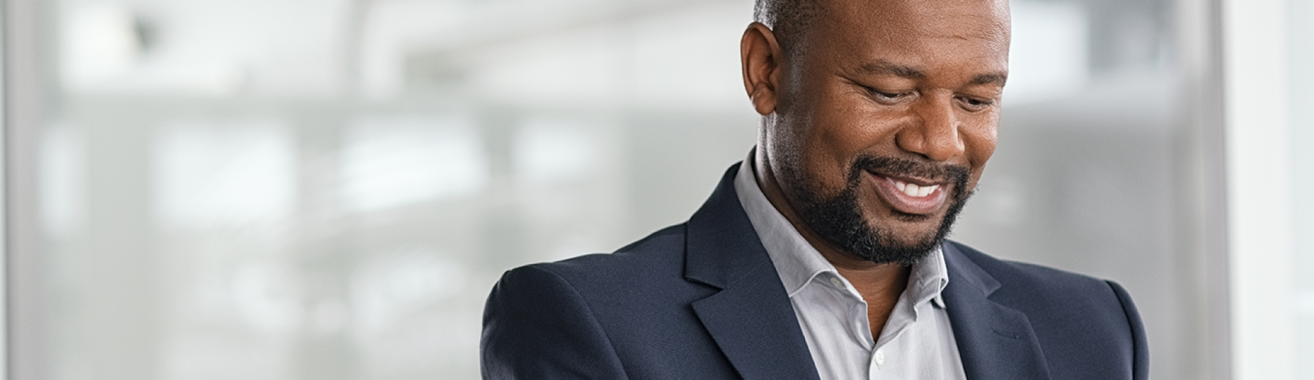 A business man wearing a suit smiles while reviewing his business bank account on computer