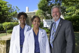 Dr. Sabrina Coombs and Dr. Stephanie Sadler wearing their white uniforms with their Eastern Bank Relationship Manager Dan Donovan 