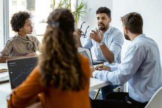 Four colleagues sit around a table and discuss a project