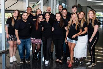 Roads Consulting Group team members stand together in branded black polo shirts and smile at the camera