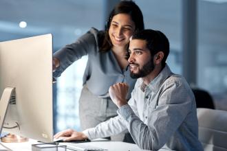 Two people review financials together on a desktop computer