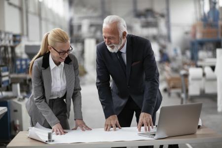 Two business owners review financials on a laptop while visiting the warehouse