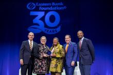 Jackie Jenkins-Scott is presented her award on stage by Eastern Bank Foundation members