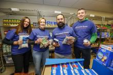 Eastern Bank employees stand together holding the food items they are volunteering to prepare
