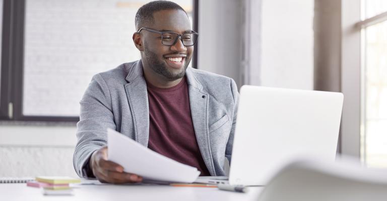 Man smiling while using laptop