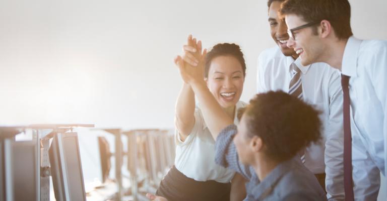Colleagues celebrate success by clapping their hands together in a high-five