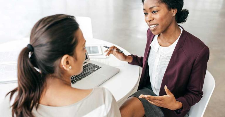 Two women sit at a table and have a discussion