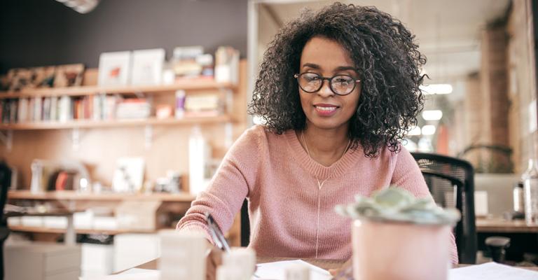 A woman sits and works at a table in a cafe 